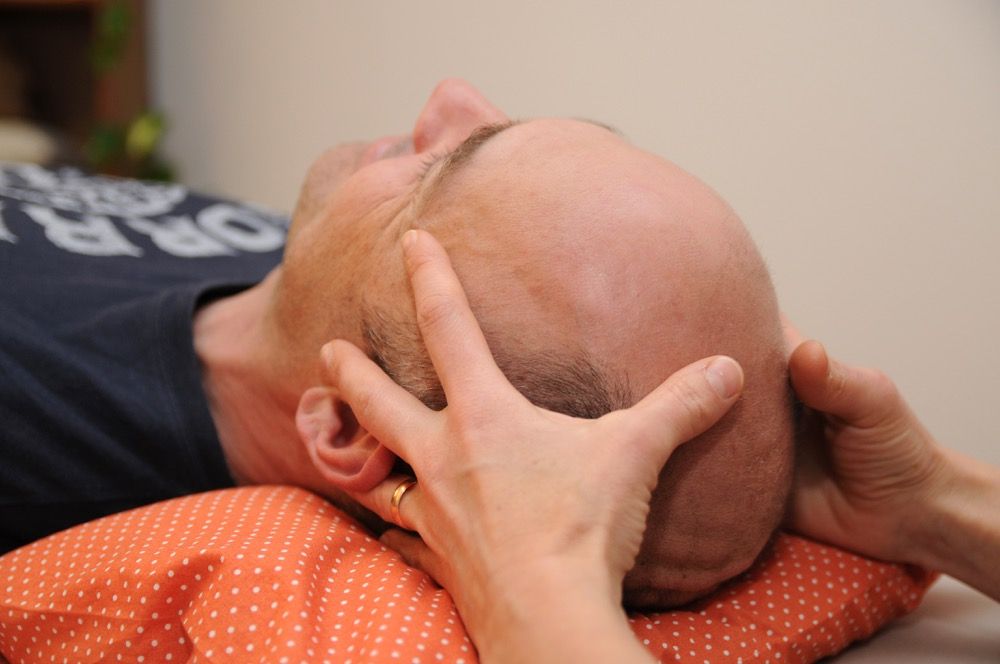 Therapeutin behandelt Kopf eines Patienten